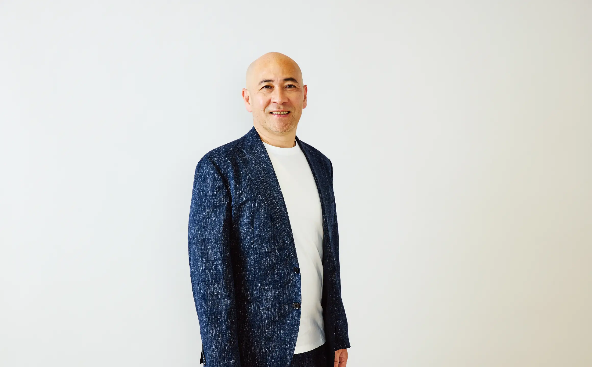 白いシャツを着た三人の男性と黒いジャケットを着た一人の男性が並んで笑顔で立っている様子。